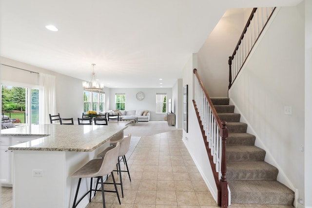 9054 Clinnin Ln, Huntley, IL 60142 - kitchen featuring healthy amount of natural light, a breakfast bar area, light stone countertops, white cabinets, and recessed lighting