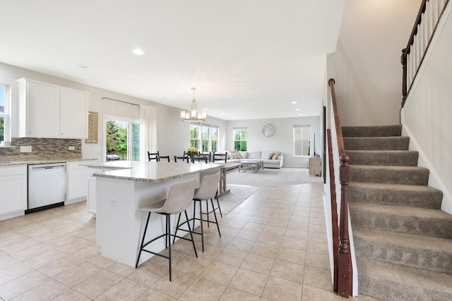9054 Clinnin Ln, Huntley, IL 60142 - kitchen with stainless steel dishwasher, a breakfast bar, light tile patterned floors, open floor plan, and white cabinetry