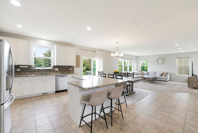 9054 Clinnin Ln, Huntley, IL 60142 - kitchen with stainless steel appliances, light tile patterned floors, a kitchen island, open floor plan, and a breakfast bar