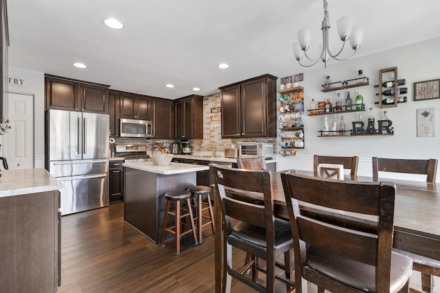 956 Tuscany Trl, Hampshire, IL 60140 - kitchen with appliances with stainless steel finishes, dark brown cabinetry, light countertops, decorative backsplash, and a center island