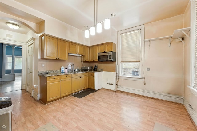 2240 S Avers Ave, Chicago, IL 60623 - kitchen featuring stainless steel microwave, light wood-style flooring, decorative light fixtures, and light stone counters