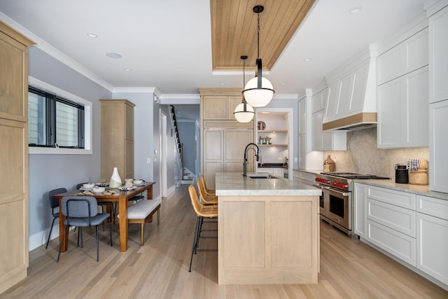 2137 W School St, Chicago, IL 60618 - kitchen featuring double oven range, light wood finished floors, premium range hood, a center island with sink, and a kitchen breakfast bar