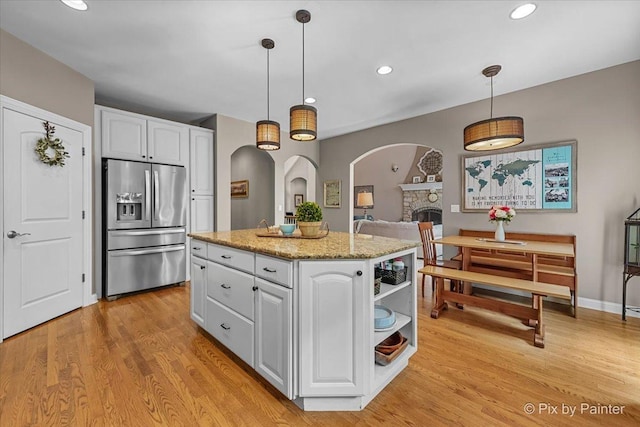 6407 Kingsbridge Dr, Cary, IL 60013 - kitchen featuring stainless steel fridge, white cabinets, arched walkways, light wood-style floors, and recessed lighting