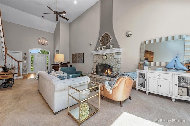 6407 Kingsbridge Dr, Cary, IL 60013 - living room featuring high vaulted ceiling, light colored carpet, a ceiling fan, a stone fireplace, and stairs