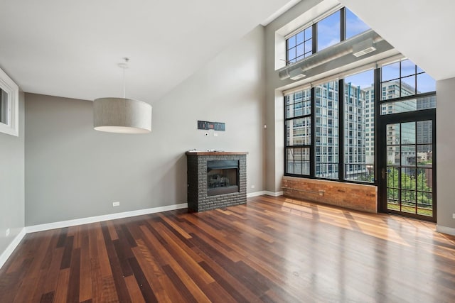 70 E 18th St Unit 4E, Chicago, IL 60616 - unfurnished living room with wood finished floors, a brick fireplace, and a towering ceiling