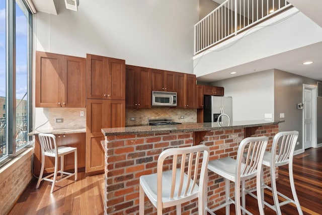 70 E 18th St Unit 4E, Chicago, IL 60616 - kitchen with stainless steel appliances, wood finished floors, a kitchen bar, tasteful backsplash, and a high ceiling