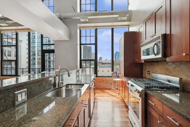 70 E 18th St Unit 4E, Chicago, IL 60616 - kitchen with stainless steel appliances, a skyline view, light wood-style floors, tasteful backsplash, and dark stone counters