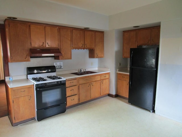 1101 N Hart St, Harvard, IL 60033 - kitchen featuring black appliances, under cabinet range hood, light flooring, brown cabinetry, and light countertops