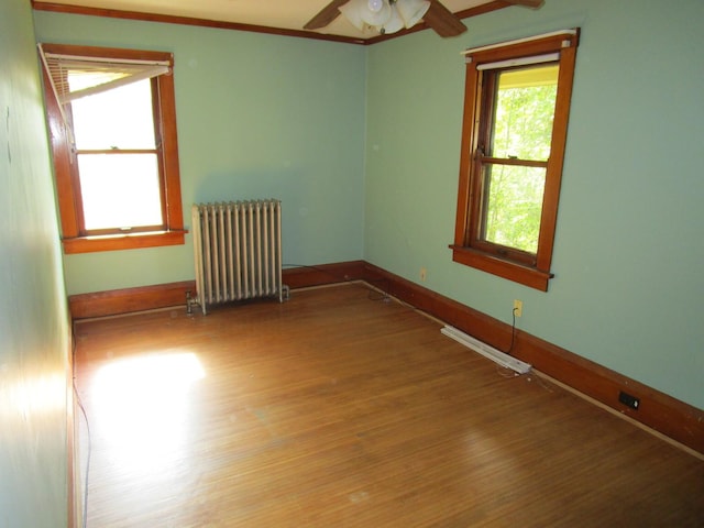 1101 N Hart St, Harvard, IL 60033 - unfurnished room featuring radiator heating unit, wood finished floors, and a ceiling fan