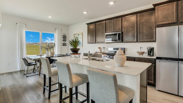 506 Adirondack Dr, Joliet, IL 60436 - kitchen with stainless steel appliances, light wood-style floors, a kitchen island with sink, a kitchen breakfast bar, and light countertops