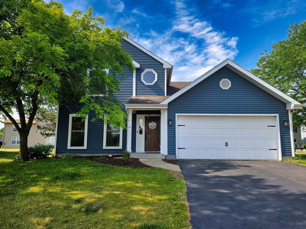 2440 Pebblewood Ct, Aurora, IL 60506 - traditional home with driveway, a front lawn, an attached garage, and a shingled roof