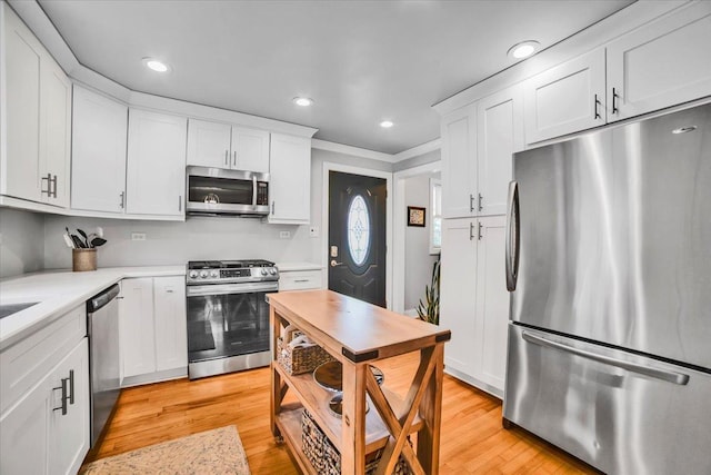 3976 Western Ave, Western Springs, IL 60558 - kitchen featuring appliances with stainless steel finishes, white cabinets, crown molding, light countertops, and light wood-style floors