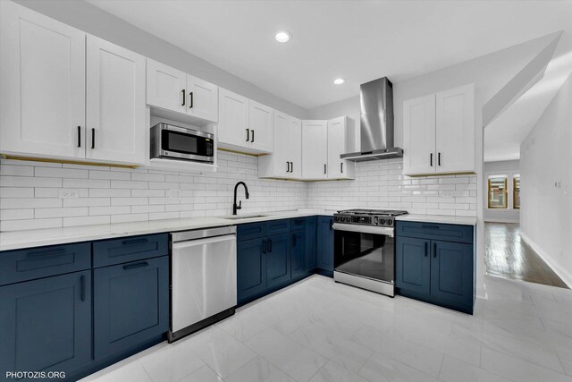 6100 W Byron St, Chicago, IL 60634 - kitchen with stainless steel appliances, wall chimney range hood, blue cabinetry, white cabinetry, and light marble finish floors