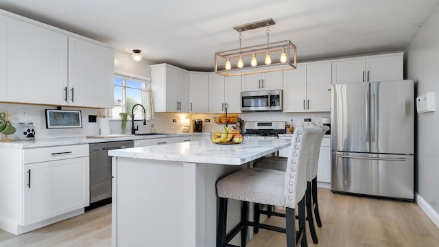 1420 Kennedy Dr, Kirkland, IL 60146 - kitchen featuring appliances with stainless steel finishes, light wood-style floors, white cabinetry, a center island, and light stone countertops