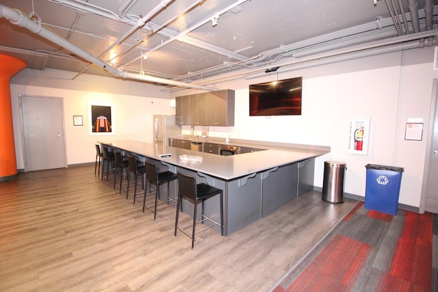 565 W Quincy St Unit 912, Chicago, IL 60661 - kitchen with freestanding refrigerator, a breakfast bar, wood finished floors, gray cabinets, and a peninsula