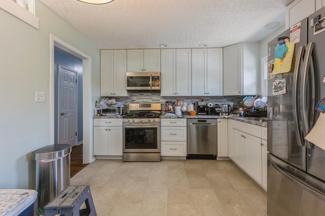 14772 Menard Ave, Oak Forest, IL 60452 - kitchen featuring appliances with stainless steel finishes, decorative backsplash, a textured ceiling, dark stone countertops, and white cabinetry