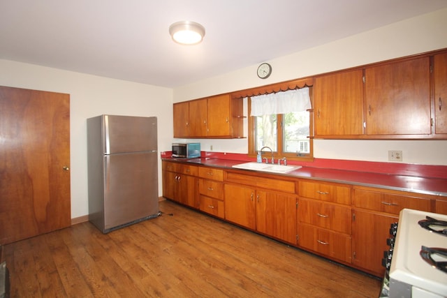 328 Dwight Ave, Joliet, IL 60436 - kitchen with appliances with stainless steel finishes, brown cabinetry, light wood finished floors, and dark countertops