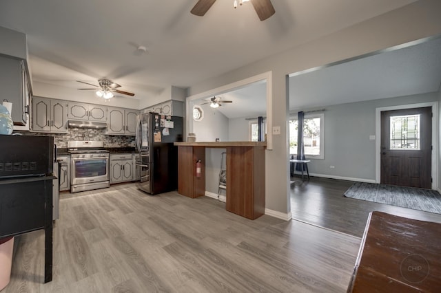 3917 Jonathan Simpson Dr, Joliet, IL 60431 - kitchen with gas range, freestanding refrigerator, a ceiling fan, under cabinet range hood, and dark countertops