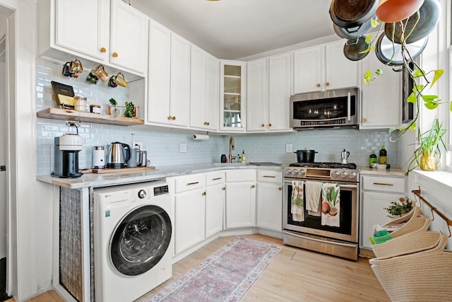4006 W Wellington Ave Unit 3, Chicago, IL 60641 - kitchen featuring appliances with stainless steel finishes, washer / clothes dryer, white cabinetry, light wood-style flooring, and backsplash