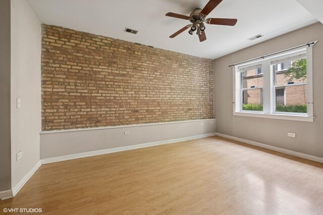4510 N Ashland Ave Unit Gw, Chicago, IL 60640 - unfurnished room featuring brick wall, a ceiling fan, and wood finished floors
