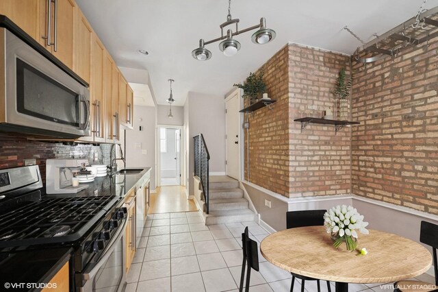 4510 N Ashland Ave Unit Gw, Chicago, IL 60640 - kitchen featuring appliances with stainless steel finishes, light tile patterned floors, backsplash, light brown cabinets, and brick wall