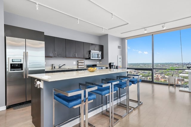 860 W Blackhawk St Unit 2106, Chicago, IL 60642 - kitchen with appliances with stainless steel finishes, track lighting, expansive windows, a kitchen island, and light wood finished floors