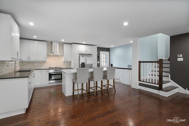 515 W Diversey Ave, Addison, IL 60101 - kitchen with appliances with stainless steel finishes, wall chimney range hood, dark wood-style floors, backsplash, and a center island