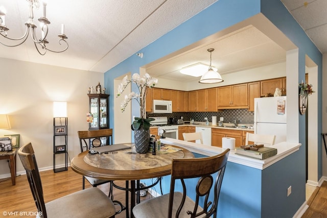 390 S Western Ave Unit 512, Des Plaines, IL 60016 - kitchen featuring white appliances, light wood-style flooring, a chandelier, tasteful backsplash, and light countertops