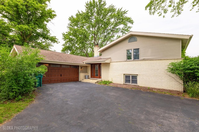 21W724 Park Ave, Lombard, IL 60148 - split level home featuring brick siding, a garage, driveway, and a chimney