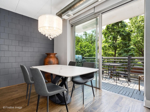 1100 W Montrose Ave Unit 207, Chicago, IL 60613 - dining space featuring wood finished floors, concrete block wall, and a chandelier