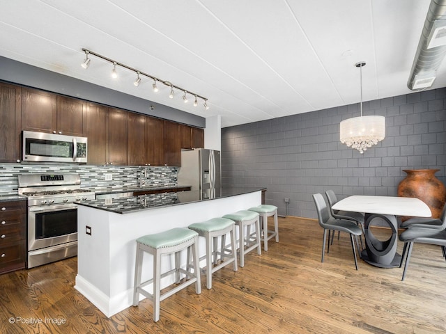 1100 W Montrose Ave Unit 207, Chicago, IL 60613 - kitchen with appliances with stainless steel finishes, a kitchen breakfast bar, dark brown cabinetry, dark wood-style floors, and a chandelier