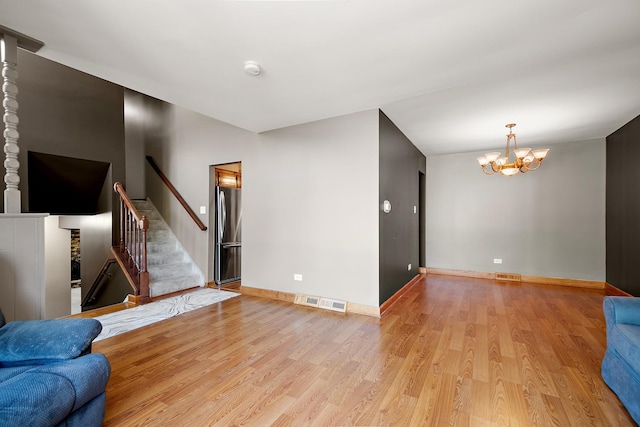 22939 E Dr, Richton Park, IL 60471 - unfurnished living room with light wood finished floors, a chandelier, and stairway
