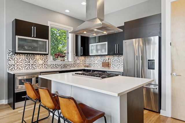 2047 N Leavitt St Unit 2N, Chicago, IL 60647 - kitchen featuring appliances with stainless steel finishes, island range hood, a breakfast bar, a kitchen island, and light countertops