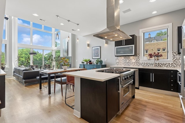 2047 N Leavitt St Unit 2N, Chicago, IL 60647 - kitchen featuring high end range, island exhaust hood, light countertops, dark cabinets, and a center island