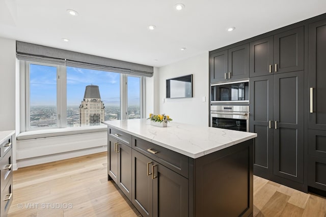 132 E Delaware Pl Unit 5101, Chicago, IL 60611 - kitchen with oven, black microwave, a kitchen island, light stone countertops, and light wood-style floors