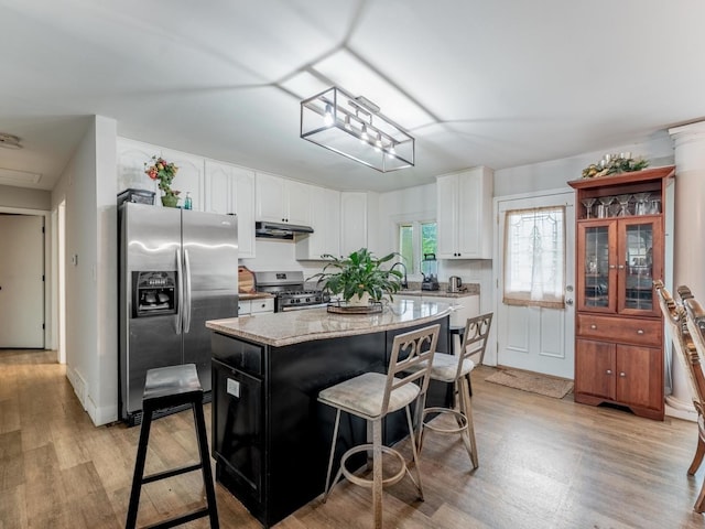 721 Lacy Ave, Streamwood, IL 60107 - kitchen with stainless steel appliances, under cabinet range hood, a kitchen breakfast bar, white cabinets, and light wood finished floors