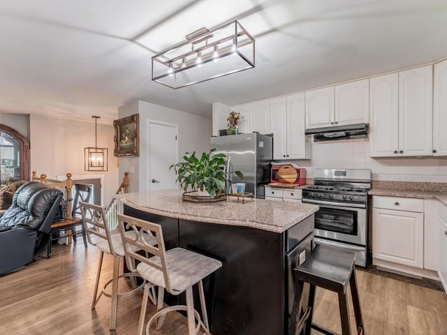 721 Lacy Ave, Streamwood, IL 60107 - kitchen with stainless steel appliances, under cabinet range hood, a kitchen breakfast bar, and white cabinets