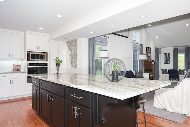 3 Laurel Ct, Galena, IL 61036 - kitchen with stainless steel appliances, a breakfast bar area, white cabinetry, light stone countertops, and recessed lighting