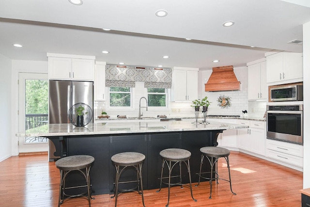 3 Laurel Ct, Galena, IL 61036 - kitchen with stainless steel appliances, custom range hood, white cabinets, light wood finished floors, and backsplash
