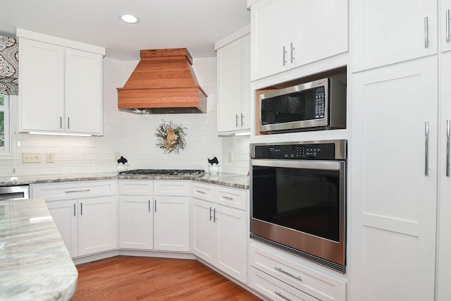 3 Laurel Ct, Galena, IL 61036 - kitchen with appliances with stainless steel finishes, custom range hood, white cabinetry, tasteful backsplash, and light wood finished floors