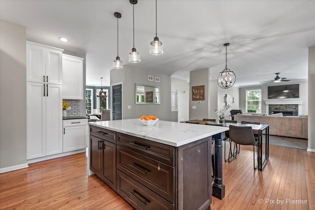 8980 Bardwell Ln, Lakewood, IL 60014 - kitchen with a fireplace, light wood-style flooring, white cabinets, a chandelier, and recessed lighting