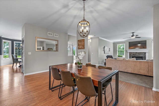 8980 Bardwell Ln, Lakewood, IL 60014 - dining area featuring light wood-style floors, a fireplace, a ceiling fan, a chandelier, and ornamental molding