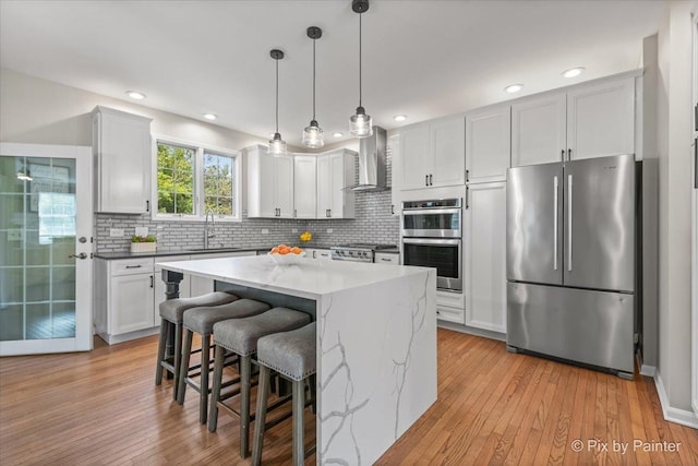8980 Bardwell Ln, Lakewood, IL 60014 - kitchen with appliances with stainless steel finishes, tasteful backsplash, light wood-style flooring, wall chimney range hood, and decorative light fixtures