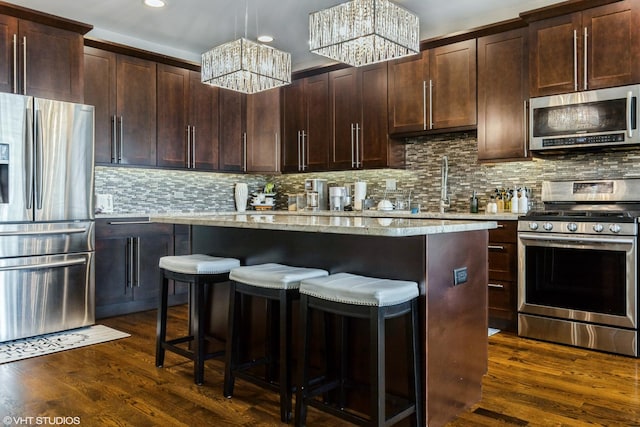 5733 S Neenah Ave, Chicago, IL 60638 - kitchen with appliances with stainless steel finishes, a chandelier, a breakfast bar, a center island, and dark wood-style flooring