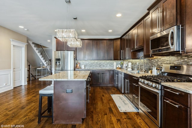5733 S Neenah Ave, Chicago, IL 60638 - kitchen with stainless steel appliances, a center island, dark brown cabinetry, light stone counters, and a breakfast bar area