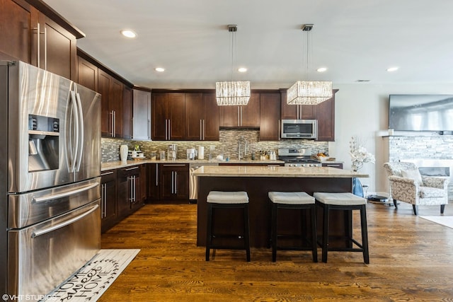 5733 S Neenah Ave, Chicago, IL 60638 - kitchen featuring appliances with stainless steel finishes, a breakfast bar, dark brown cabinets, decorative backsplash, and a kitchen island