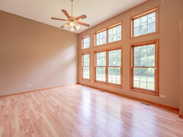 2207 Irvine Ln, Plainfield, IL 60586 - unfurnished room featuring light wood-style floors, a ceiling fan, and a towering ceiling