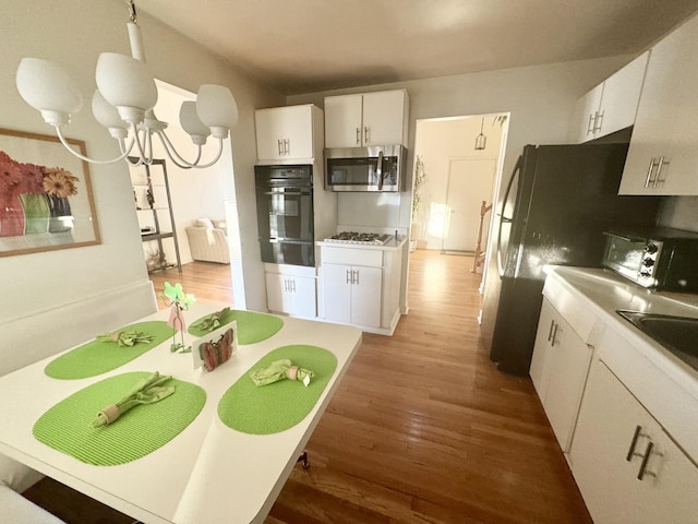 8142 N Chester Ave, Niles, IL 60714 - kitchen featuring oven, stainless steel microwave, wood finished floors, a warming drawer, and white cabinets