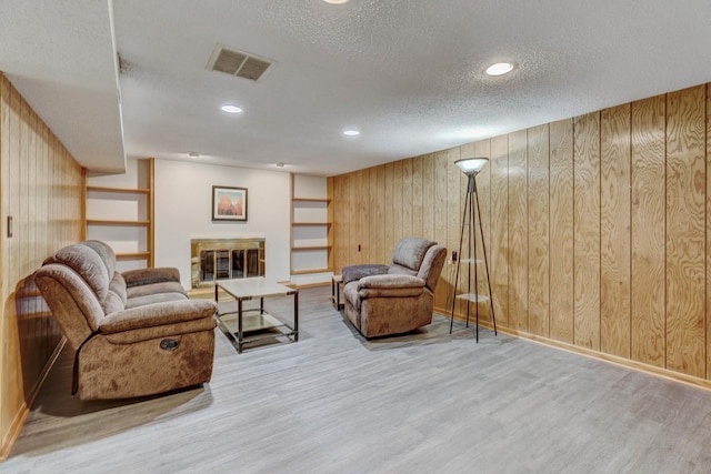 9810 N Lauren Ln, Niles, IL 60714 - living area featuring wooden walls, wood finished floors, a textured ceiling, recessed lighting, and a glass covered fireplace