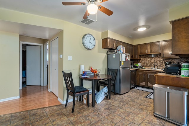 629 N Carroll Pkwy Unit 207, Glenwood, IL 60425 - kitchen with freestanding refrigerator, dark brown cabinets, backsplash, a ceiling fan, and dark stone finish floors